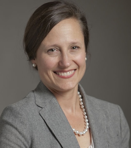 Portrait of a smiling researcher wearing a gray blazer and pearl necklace.
